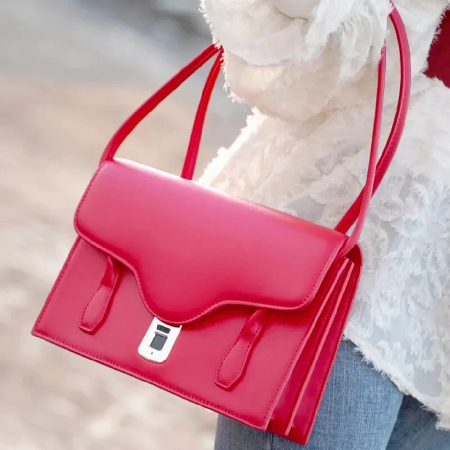 Scarlet Elegance Handbag: A vibrant red handbag featuring a sleek design, gold-toned clasp, and a patterned fabric handle, embodying elegance and style.